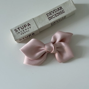 Detailed view of the soft pink silk ribbon bow hair clip with a smooth satin texture