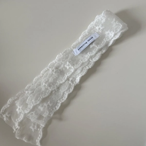 Close-up of white mesh lace ribbon featuring delicate floral embroidery and textile label