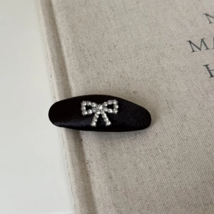 Elegant black satin hair clip featuring a sparkling rhinestone bow for women