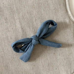 Detailansicht der Jeans-Stoffschleife Haarspange auf einem natürlichen Leinenhintergrund