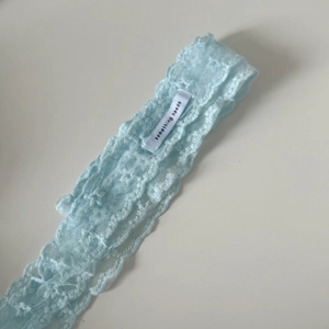 Detail of light blue star lace ribbon with intricate textures and brand label