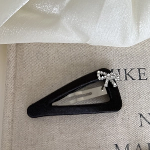Close-up of a black satin BB hair clip with a sparkling silver rhinestone bow detail