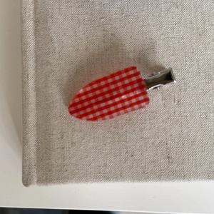 Detail of red and white gingham hair clip with silver metal alligator clamp on fabric