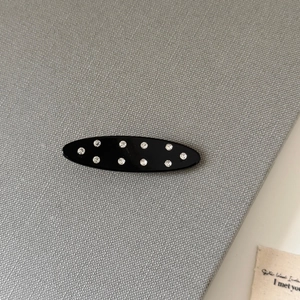 Détail d'une pince à cheveux ovale noire ornée de strass brillants sertis à la main