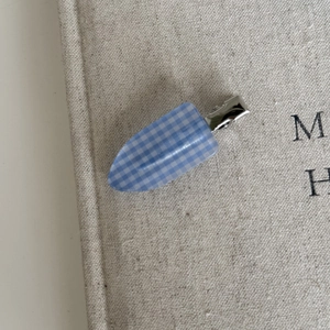 Detailed macro view of the blue and white checkered hair clip on beige linen fabric