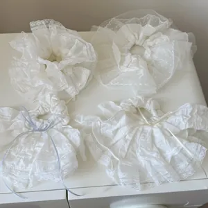 Dettaglio di elastici per capelli in pizzo bianco con volant e fiocchi