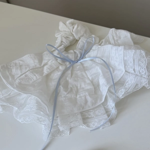 Vista dettagliata dell'elastico in pizzo bianco con un delicato fiocco di nastro azzurro