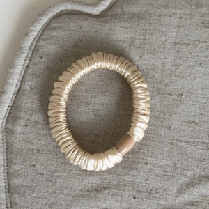 Primo piano dettagliato dell'elastico per capelli in raso oro champagne con fibbia in resina