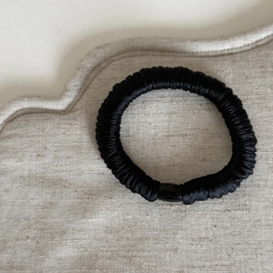 Dettaglio dell'elastico per capelli nero senza cuciture effetto seta con fibbia cilindrica