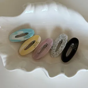 Detailed set of acetate oval hair clips with marble textures on a shell tray