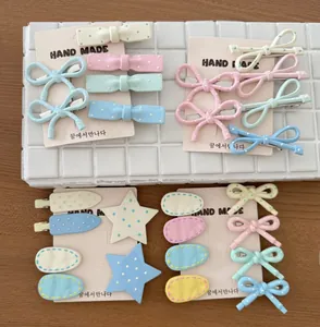 Detail of cream-colored handmade hair clips with dots and stars on beige cards