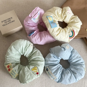 Detailed view of pastel macaron hair scrunchies with embroidered fruit and smile patches