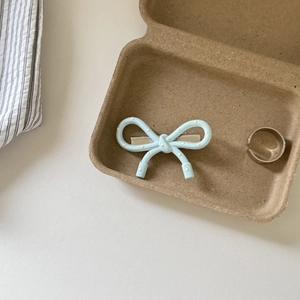 Close-up of cream polka dot bow hair clip and minimalist silver ring on a tray