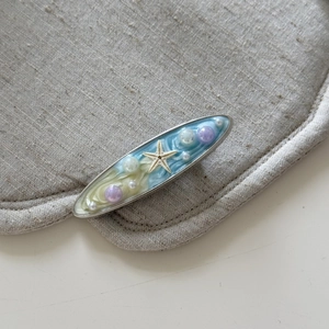 Dettaglio del fermaglio per capelli stile marino con stella marina blu e perle lucide