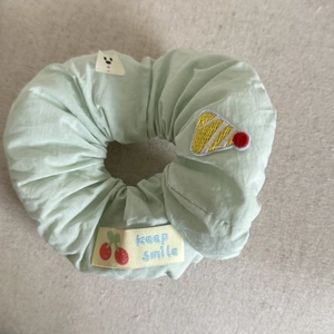 Close-up of mint green fabric scrunchie with cute bear patch and cherry embroidery details