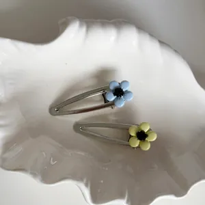 Blue and yellow floral metal hair clips set on a decorative white shell tray