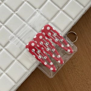 Detailed view of three red polka dot metal BB hair clips in clear packaging