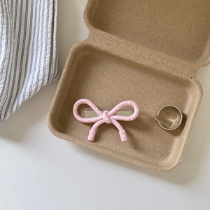 Detail of pink polka dot bow hair clip and polished silver open ring in a box