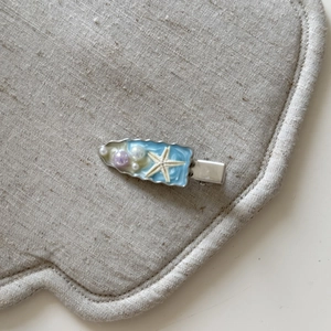 Dettaglio ravvicinato di un fermaglio per capelli a stella marina blu con perle e base argento