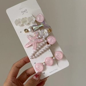 Détail de lot de 5 barrettes thème marin avec coquillages roses et étoiles de mer sur carte