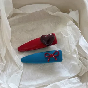 Simpatiche mollette per capelli rosse e blu con fiocco e cuore su carta bianca
