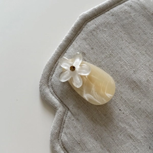 Detailed macro view of an ivory floral hair clip featuring marble texture and a rhinestone center