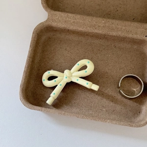 Detail of cream yellow bow hair clip with blue dots and silver ring in gift box