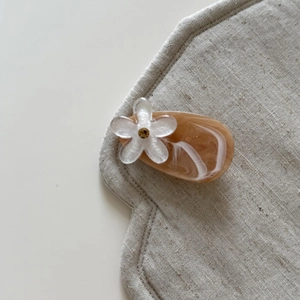 Close-up of marble amber resin hair clip with pearl flower and gold center detail