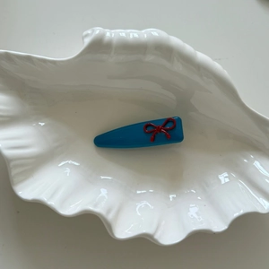 Fermaglio per capelli blu minimalista con fiocco rosso su vassoio a conchiglia, dolce