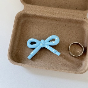 Detail of light blue polka dot bow hair clip and silver ring in eco-friendly gift box