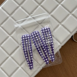 Close-up of purple and white checkered hair clips in a three-piece set packaging
