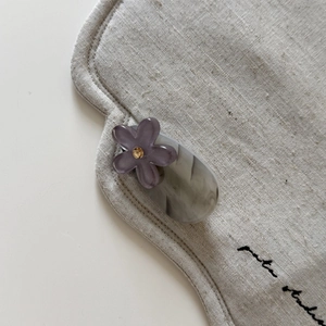 Close-up of floral hair clip with purple flower and yellow crystal on marble pattern