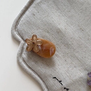 Close-up of amber marble hair clip with a delicate floral rhinestone detail on linen fabric