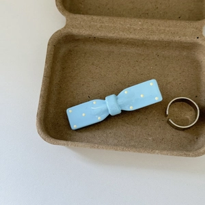 Close-up of light blue bow hair clip with yellow polka dots and silver metal ring