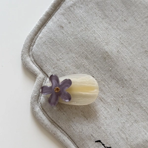 Close-up of a floral rhinestone hair clip with marble texture on a soft linen fabric