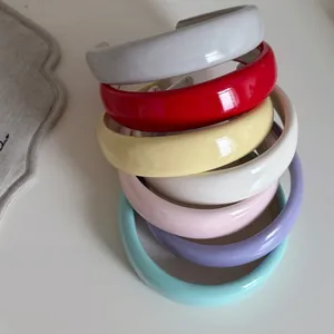 Close-up of vibrant candy-colored glossy patent leather sponge headbands in seven colors