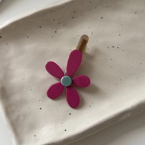 Dettaglio del fermaglio per capelli a fiore rosa in resina su vassoio ceramico