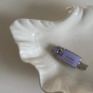 Macro shot of purple enamel hair clip with silver cherry crystal detail and wave edge