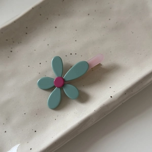 Dettaglio di un fermaglio per capelli a fiore carino in ciano e rosa su un piatto di ceramica