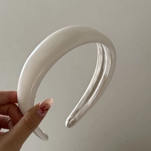 Detail of white padded sponge headband in shiny patent leather for a vintage voluminous look