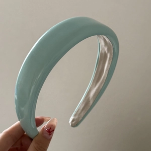 Close-up of a light blue padded headband with shiny faux leather finish and non-slip lining