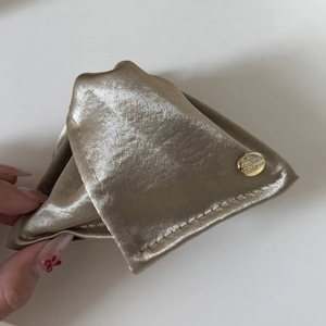 Close-up of champagne gold triangle hair claw clip with satin fabric and metal tag
