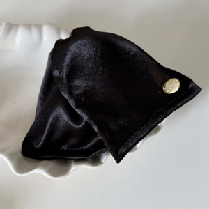 Close-up of a black velvet triangle hair claw clip with an elegant gold metal brand tag