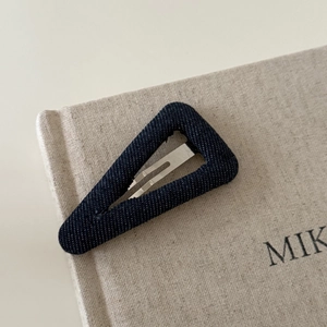 Vintage blue denim triangle BB hair clip with silver metal fastener on beige background