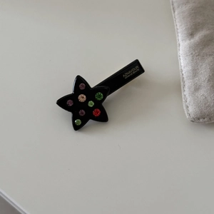 Close-up of star-shaped hair clip with colorful rhinestones and brand logo print