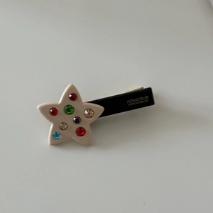 Detailed macro view of cream star hair clip with multi-colored rhinestones and black base