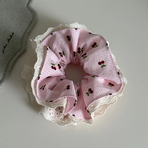 Gros plan du chouchou à carreaux roses avec motifs de cerises et broderie en dentelle