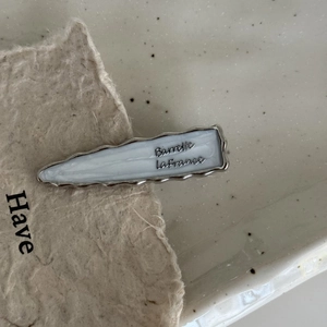 Detail of cream resin hair barrette with silver frame and Barrette LaFrance text