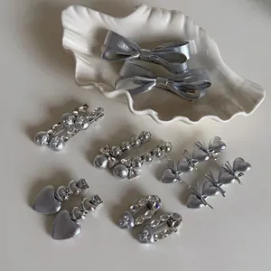 Ensemble élégant de barrettes argentées à nœud et cœur sur un plateau blanc chic