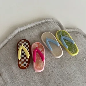 Set of four colorful flip-flop shaped acetate hair clips on textured fabric background